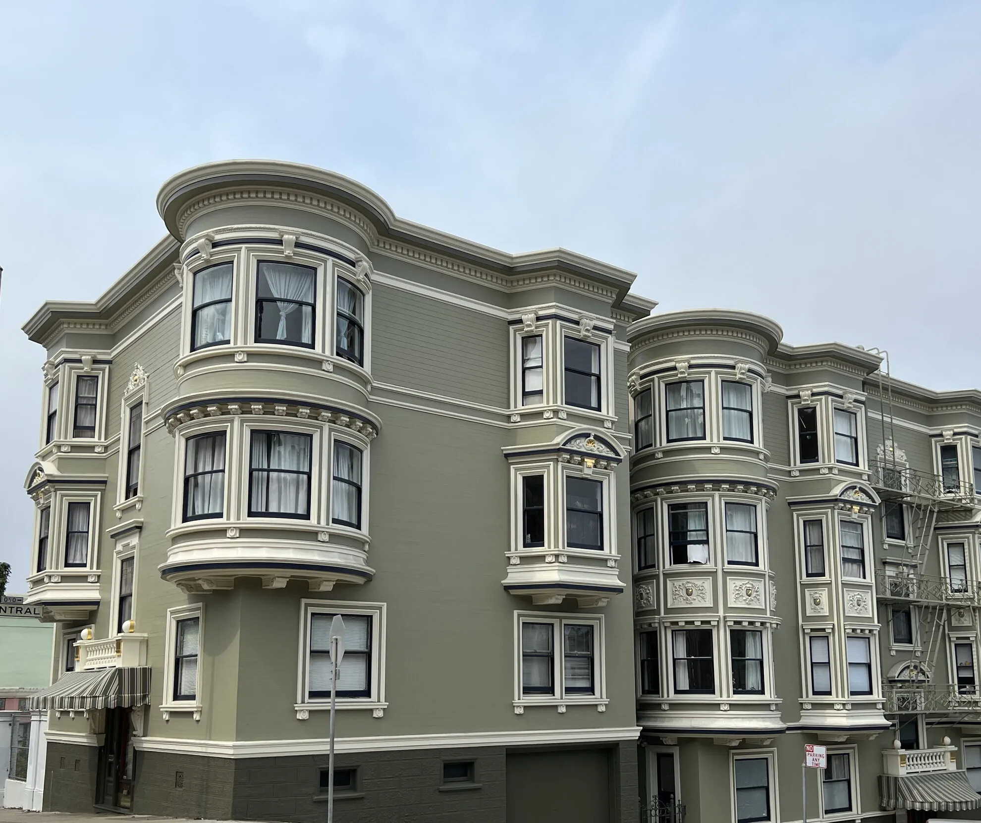 Sage-green San Francisco apartment building with bay windows and white trim, repainted by Tara Pro